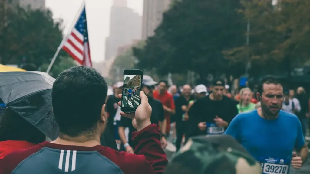 Spectator films runners as they near the north east corner of Central Park in Harlem during one of best marathons in the us new york city marathon