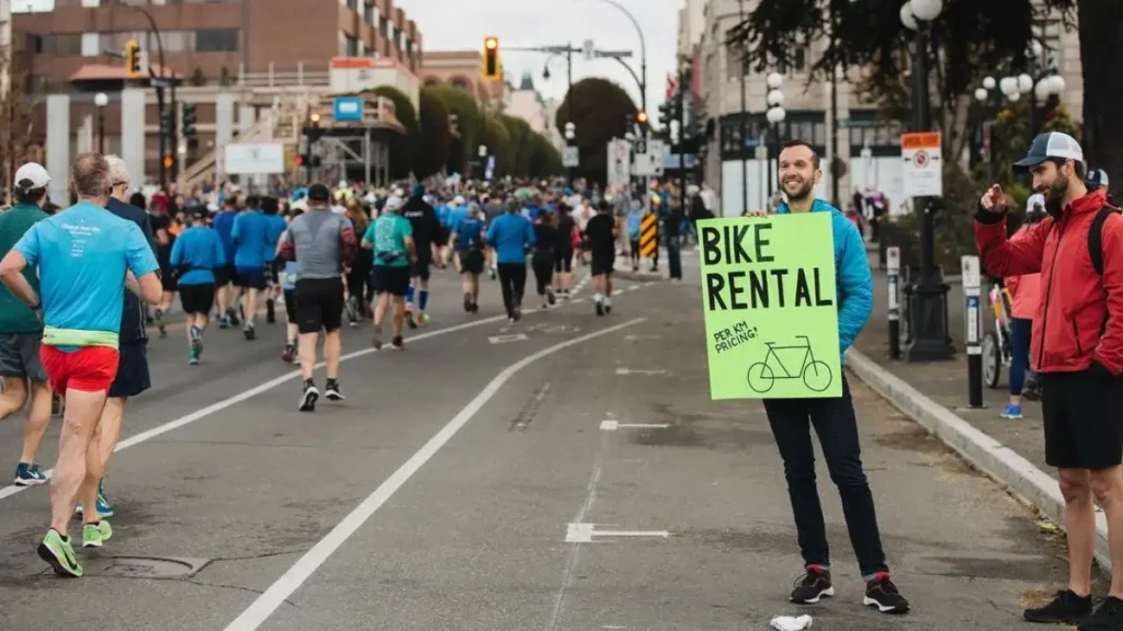 supporter holding a marathon race sign idea that says bikes for rent