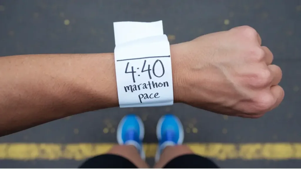 a piece of paper that has been wrapped around the wrist of a runner. the paper is blank, white, but has the words "4:40 Marathon Pace" written on it in pen. the image is POV of the runner.