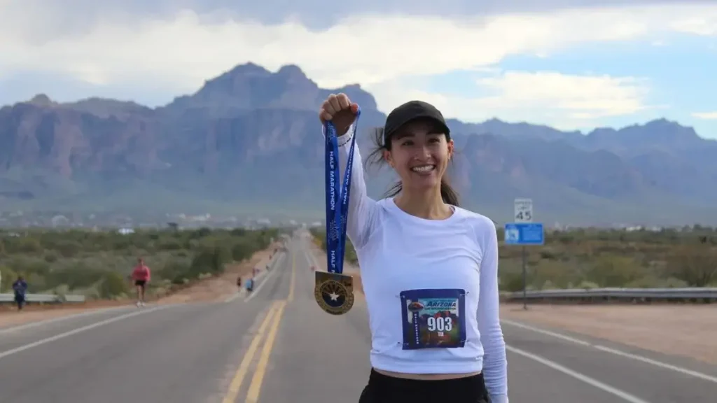 A runner holds up her finisher’s medal in the sunlight at the Lost Dutchman Marathon in Apache Junction.