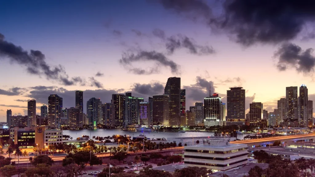 The skyline shines brightly at night over Biscayne Bay in Miami, Florida.