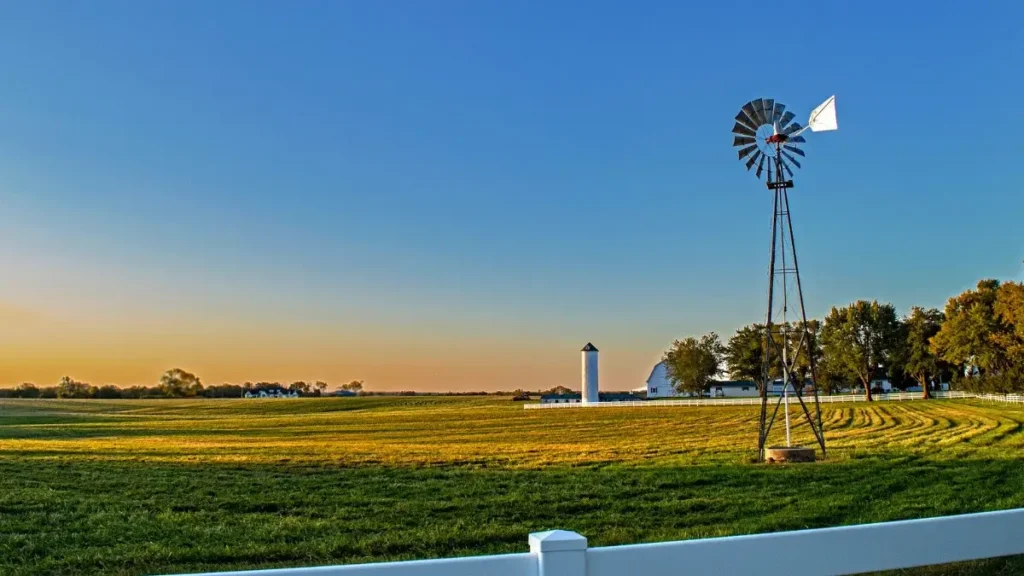 Farmland view in Abilene, Kansas, home of the Eisenhower Marathon, with a windmill and barn at sunset.