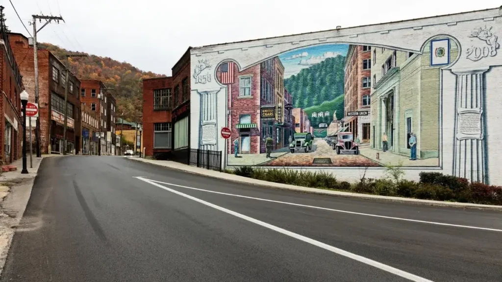 A colorful mural on a building wall in a West Virginia town with surrounding hills, representing the best marathons in West Virginia.